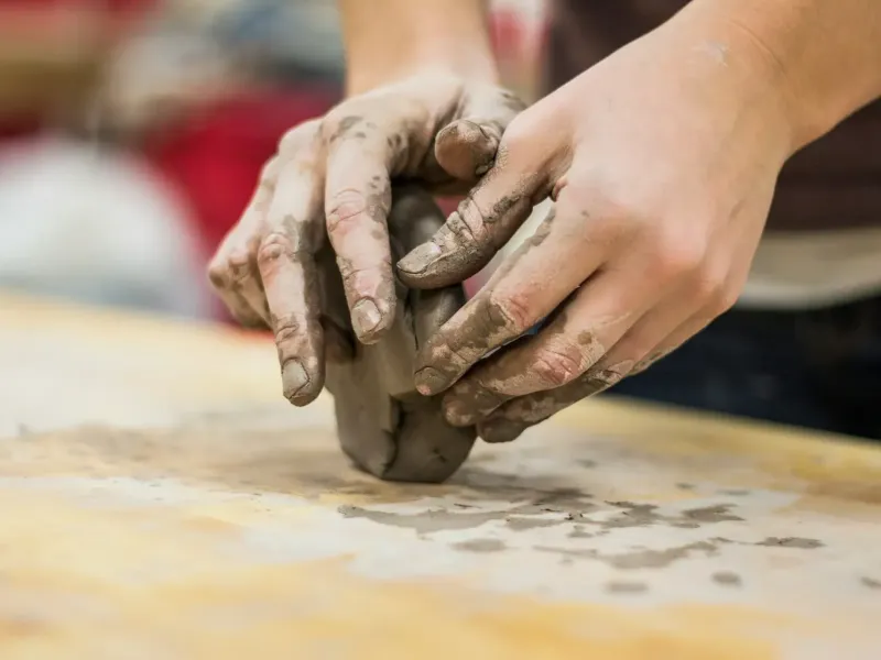 Hände formen Lehm auf einer Holzplatte - Handwerk des traditionellen Ziegelbrennens am Unterstandroahof