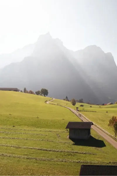 Nahaufnahme des Unterstandroahofs mit grünen Wiesen und Bergpanorama im Hintergrund
