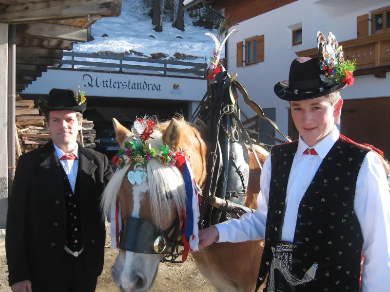 Zwei Männer in traditioneller Südtiroler Tracht bei einem Umzug mit einem Pferd