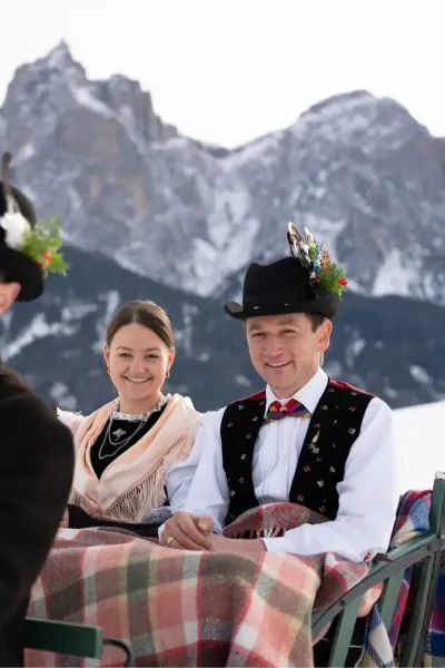 Frau und Mann in Südtiroler Tracht vor dem Unterstandroahof mit dem Schlernmassiv im Hintergrund