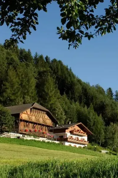 Außenansicht des Unterstandroahofs im Sommer mit gepflegtem Garten und Bergwiesen ringsum