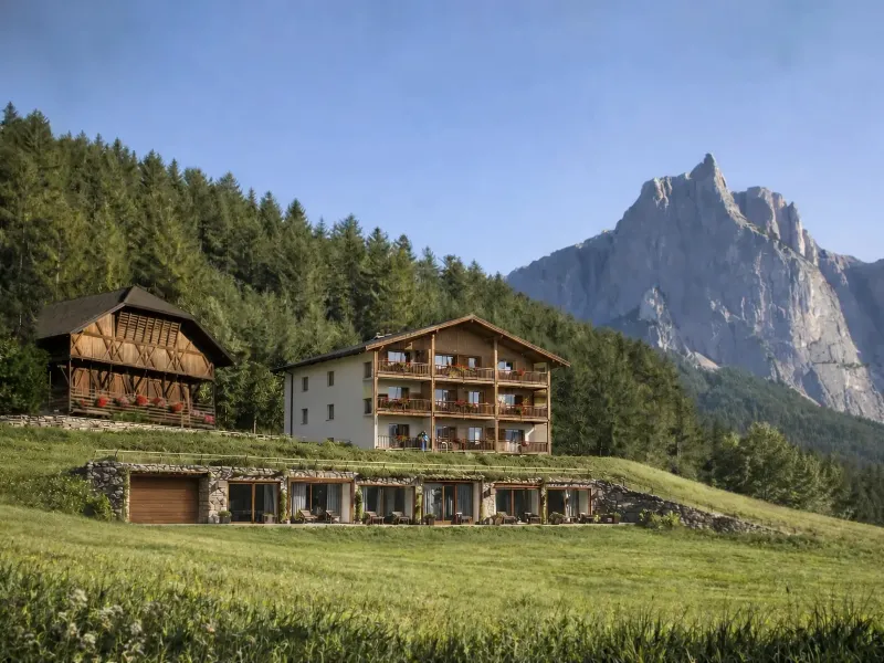Luftige Bergwiese mit Blick auf den Unterstandroahof und das Schlernmassiv im Morgenlicht