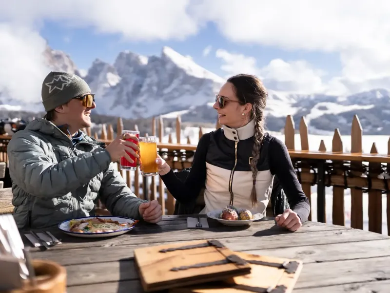 Zwei Personen beim Essen an einem Tisch im Freien mit Bergpanorama