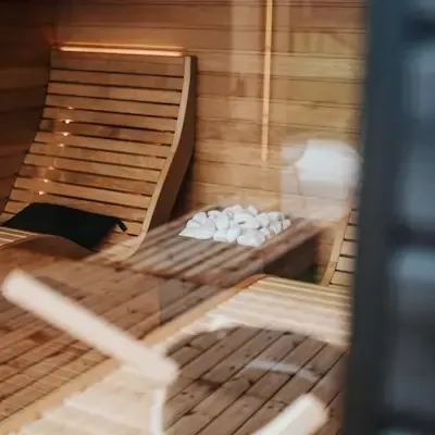 Innenansicht einer Sauna mit zwei Holzliegen und einem schwarzen Kissen