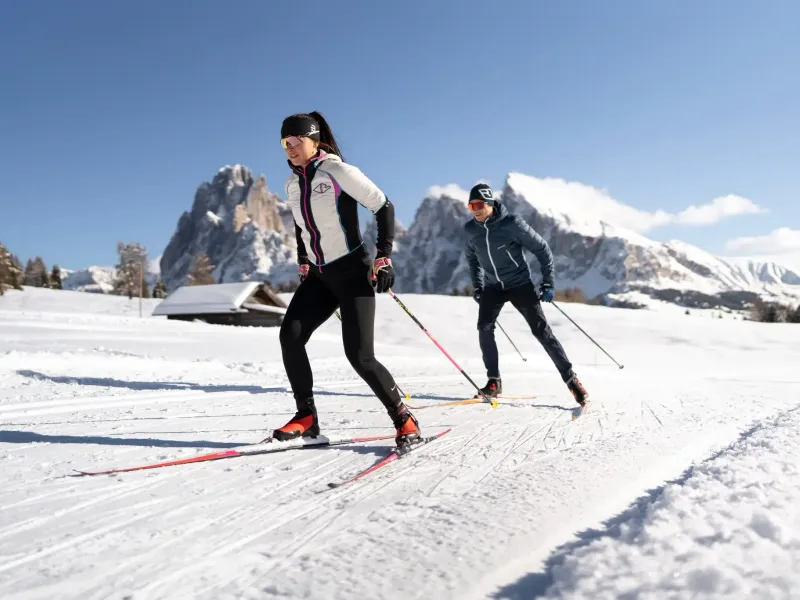Zwei Langläufer auf einer verschneiten Loipe in der Winterlandschaft